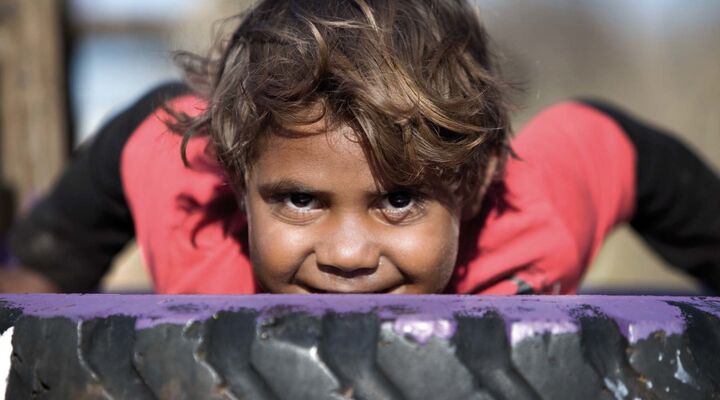 Aboriginal Child On A Tyre Looking Into Camera