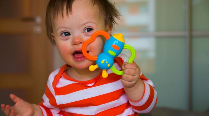 Cute Baby Boy With Down Syndrome Holding Coloured Butterfly Toy
