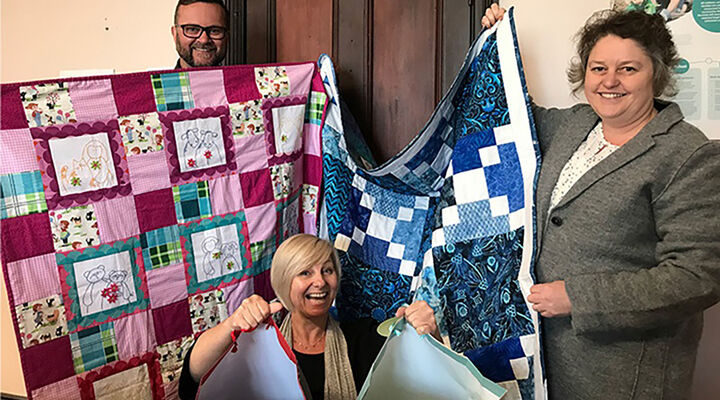 MacKillop's NSW team members holding quilts